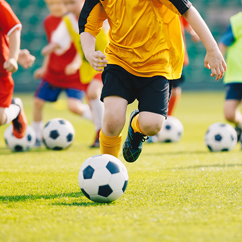 Group of school children running and kicking soccer balls